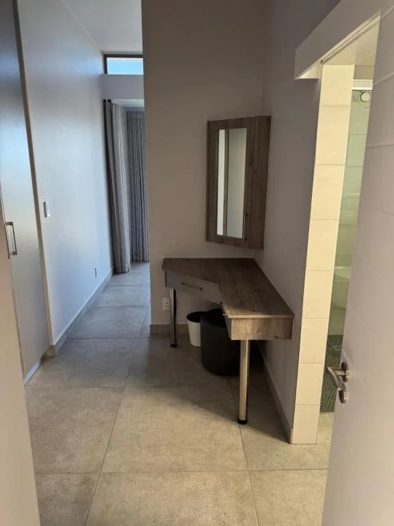 Modern hallway with vanity mirror, wooden bench, and bathroom access