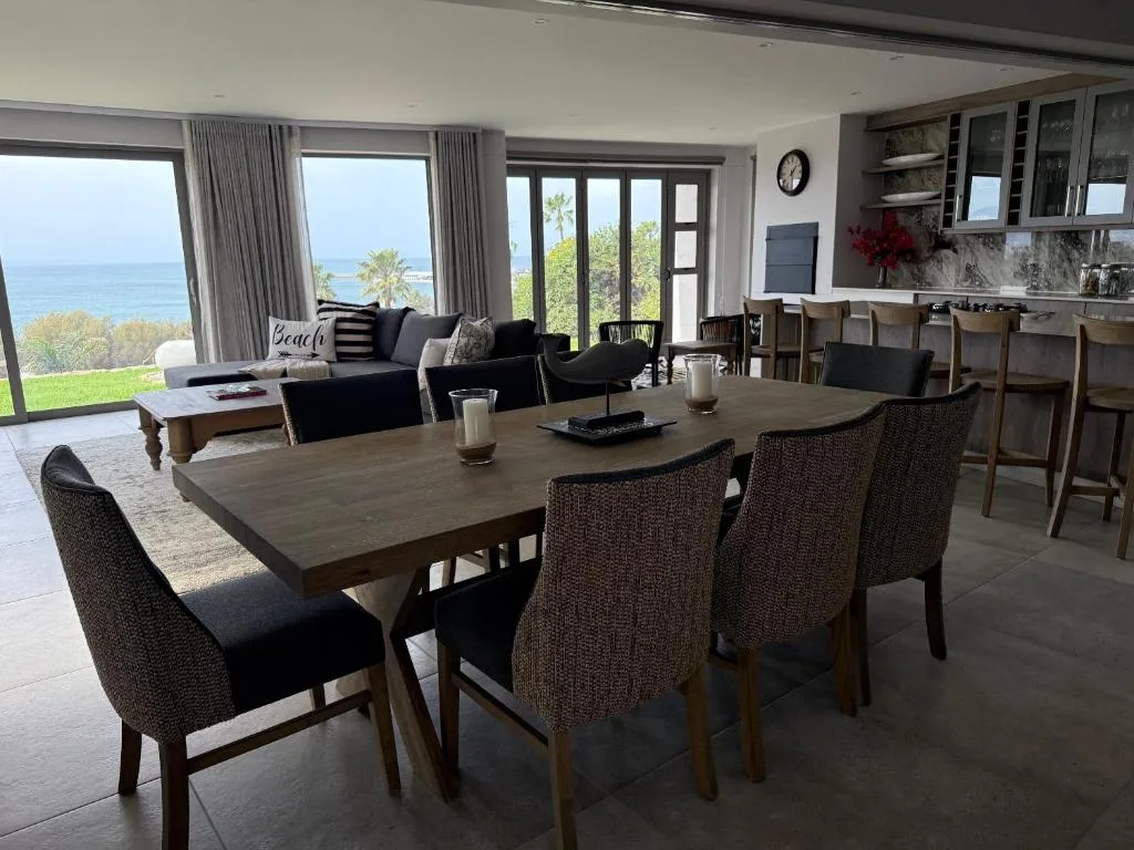Spacious dining area with wooden table and ocean views through large windows