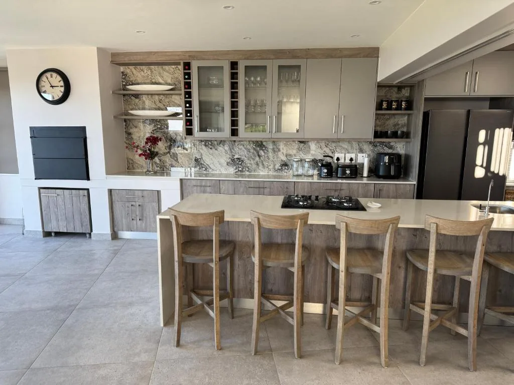 Modern kitchen with marble backsplash, grey cabinetry, and island seating for four