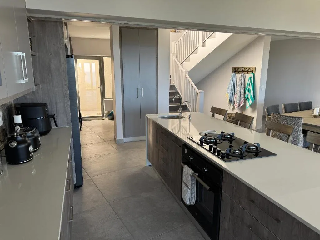 Modern kitchen with gas cooktop, white countertops, and dark cabinetry