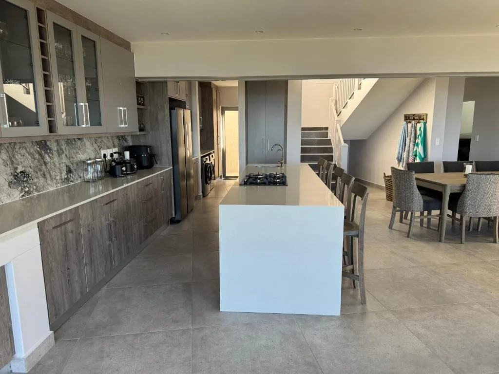 Modern kitchen with island, marble backsplash, stainless steel appliances, and open-plan dining area