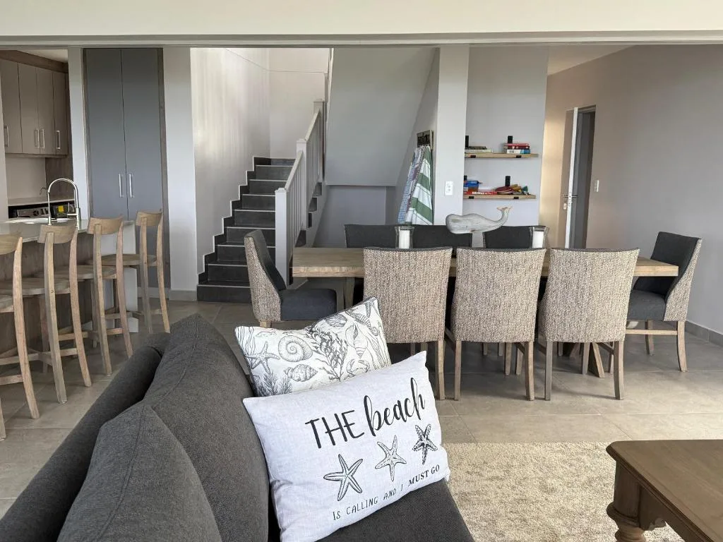 Open-plan lounge with gray sofa, dining area, and kitchen visible