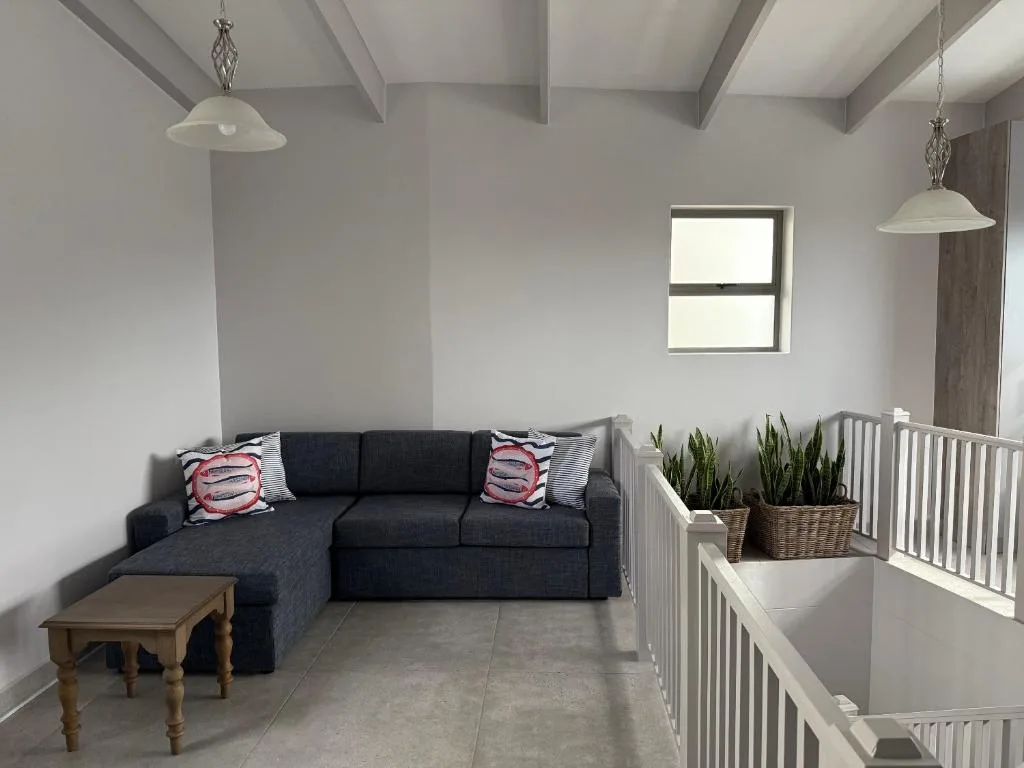 Modern lounge with dark sectional sofa and decorative cushions, pendant lighting