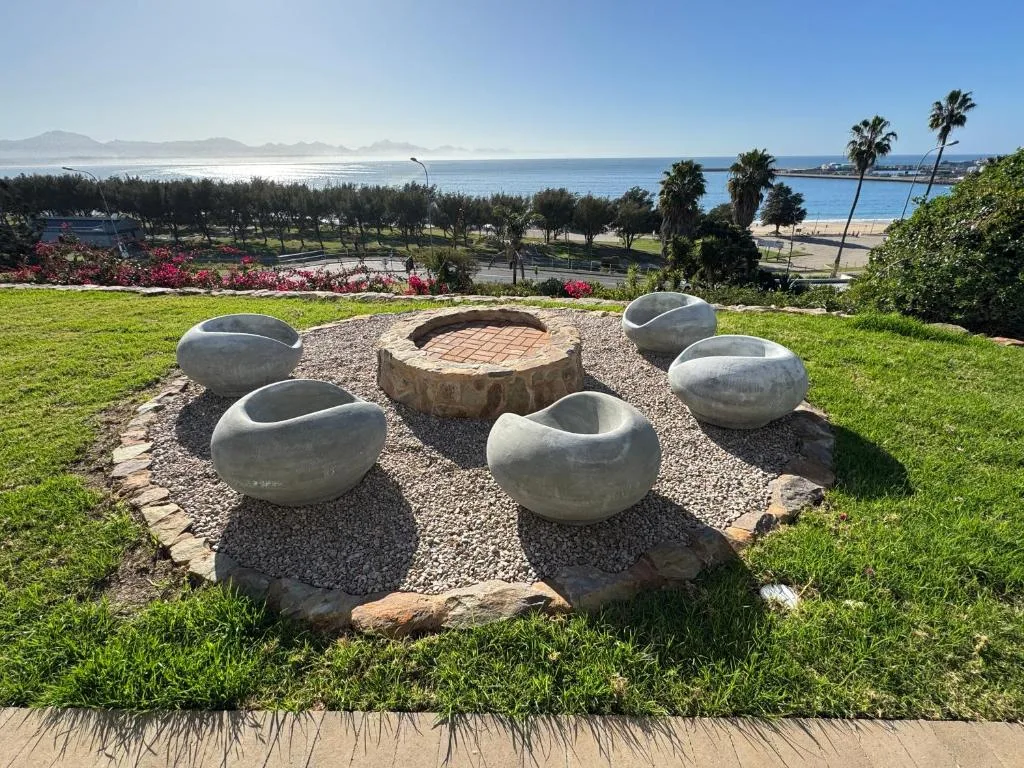 Coastal garden view with ocean, mountains, and palm trees in distance