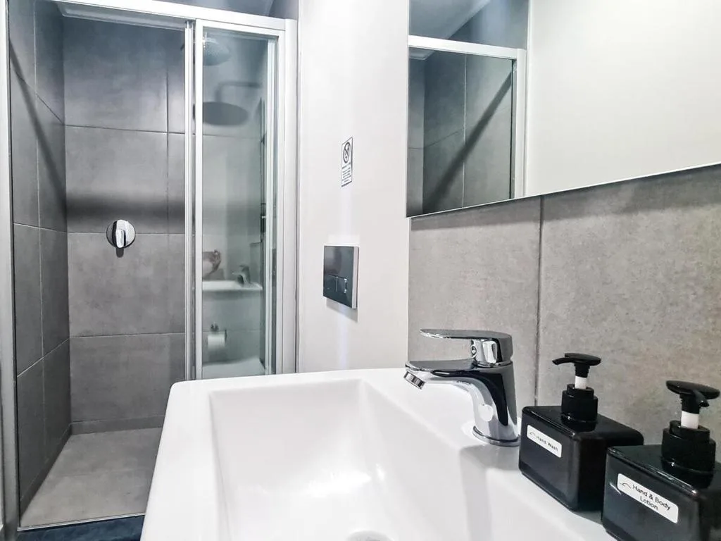 Modern bathroom with white sink, black faucet, and walk-in shower