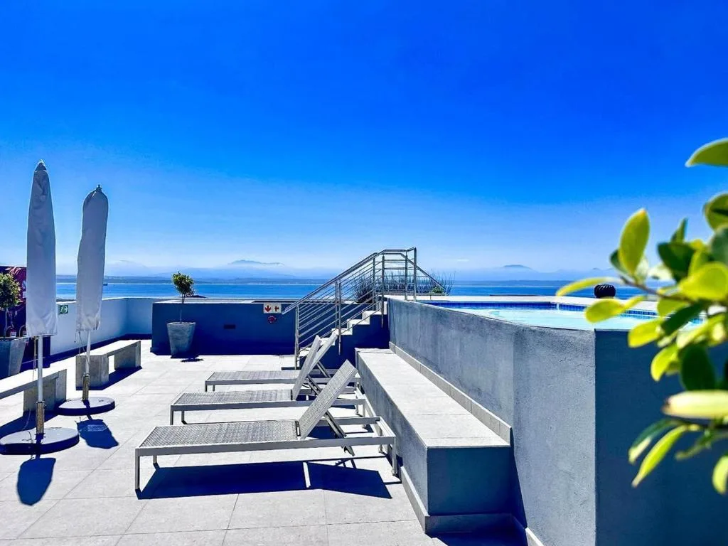 Sunlit rooftop deck with lounge chairs overlooking blue ocean and distant islands