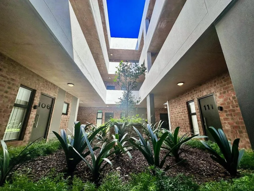 Modern courtyard entrance with skylights, brick walls, and planted gardens
