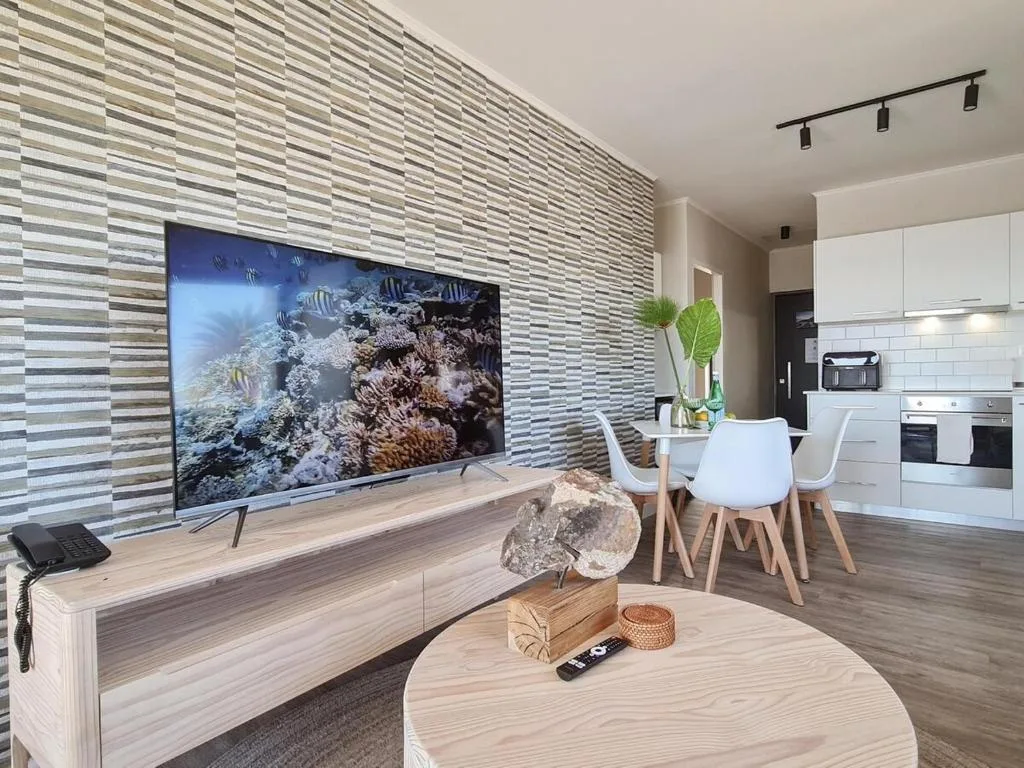 Modern lounge with TV, striped accent wall, and ocean-themed decor