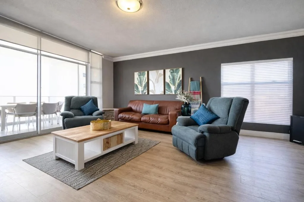 Modern lounge with brown leather sofa and blue armchairs, wooden coffee table