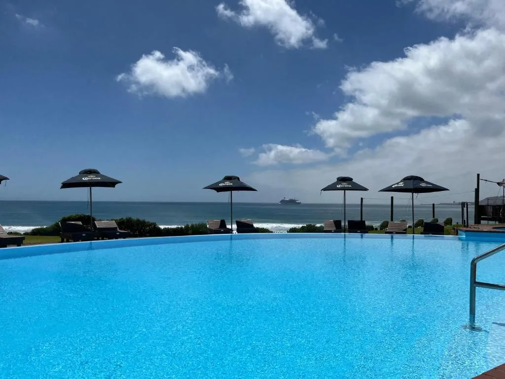 Oceanfront swimming pool with umbrellas overlooking Mossel Bay beach