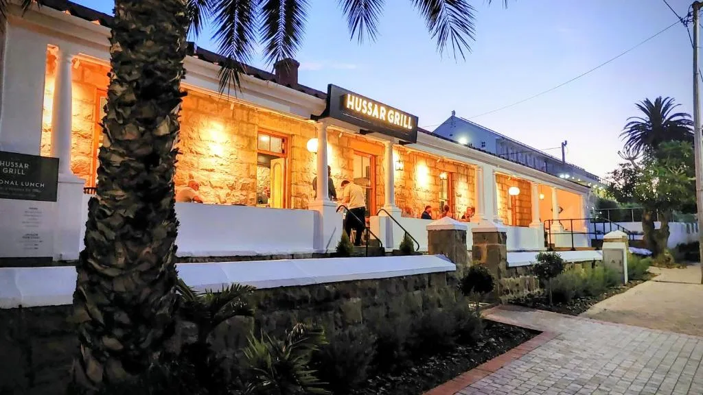 Modern white building facade with warm evening lighting and palm trees