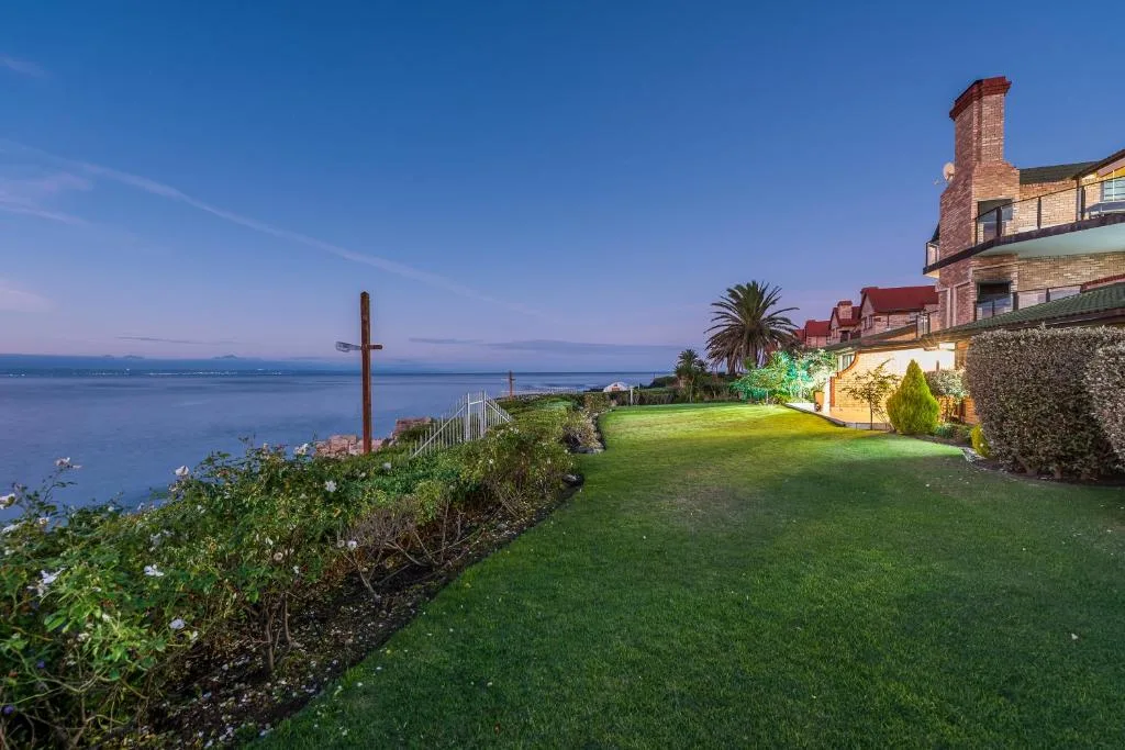 Oceanview from manicured lawn with historic building and cross overlooking blue water
