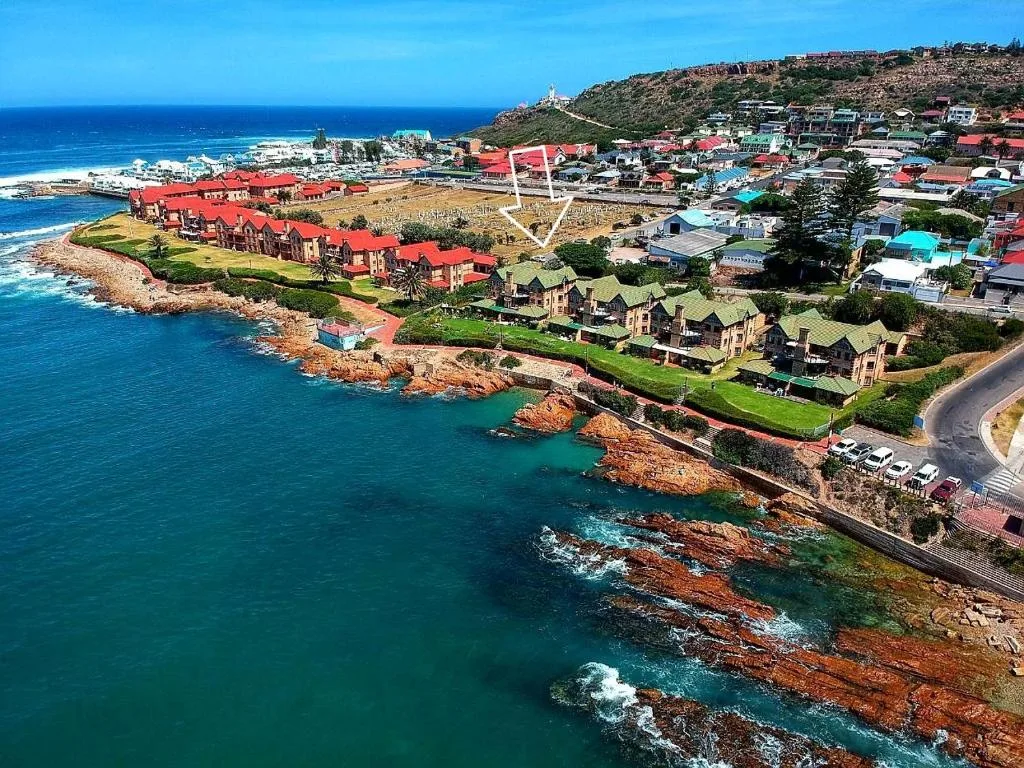 Aerial view of coastal town with turquoise ocean and rocky shoreline