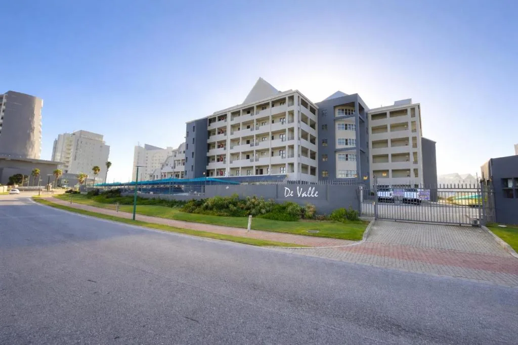Modern De Valle apartment building with manicured grounds and entrance gate