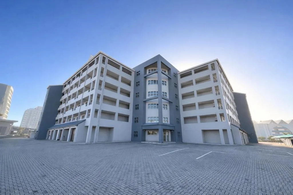 Modern multi-story apartment building with white and grey facade and parking area