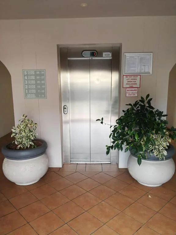 Building elevator entrance with potted plants and safety signage