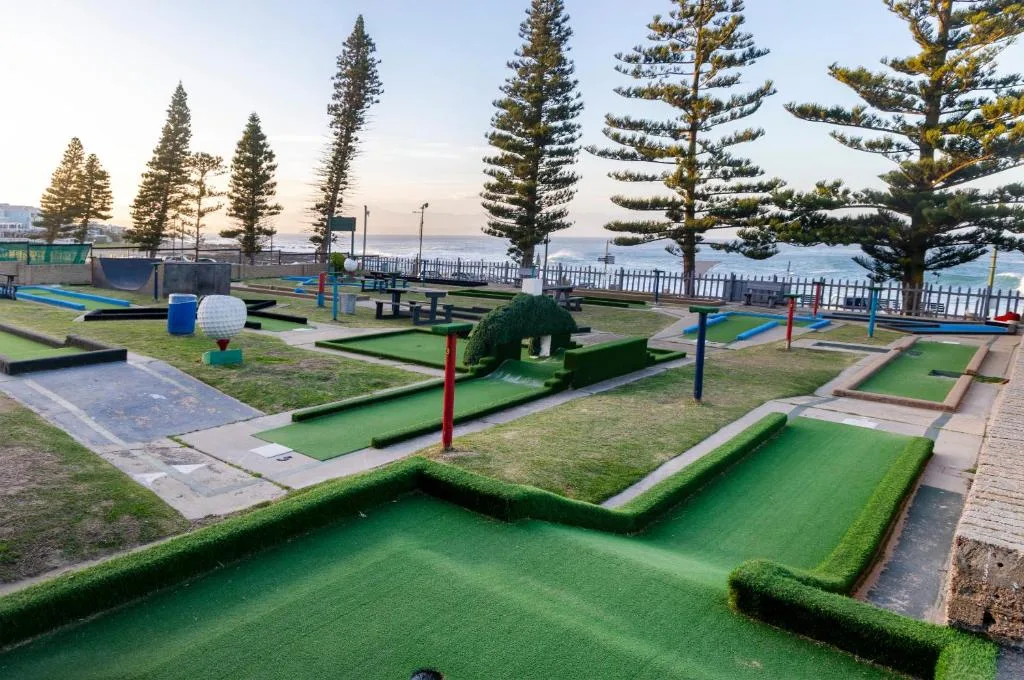 Miniature golf course with ocean and pine trees in background