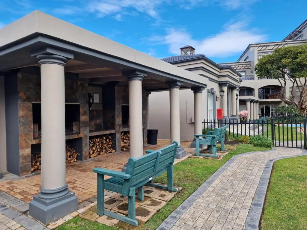 Covered patio with columns, benches, fireplace, and manicured gardens