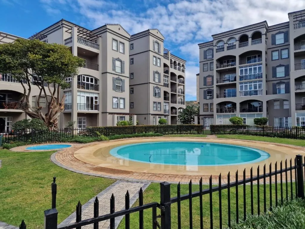 Turquoise circular swimming pool surrounded by manicured lawn and brick paving