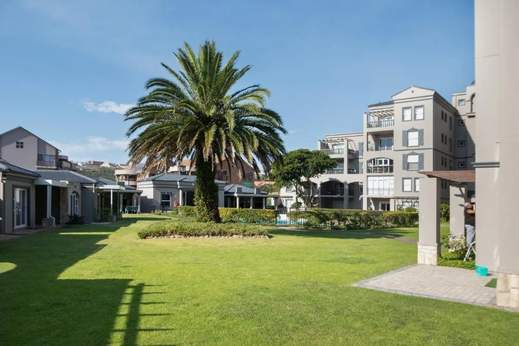 Spacious manicured lawn with palm tree and modern apartment buildings