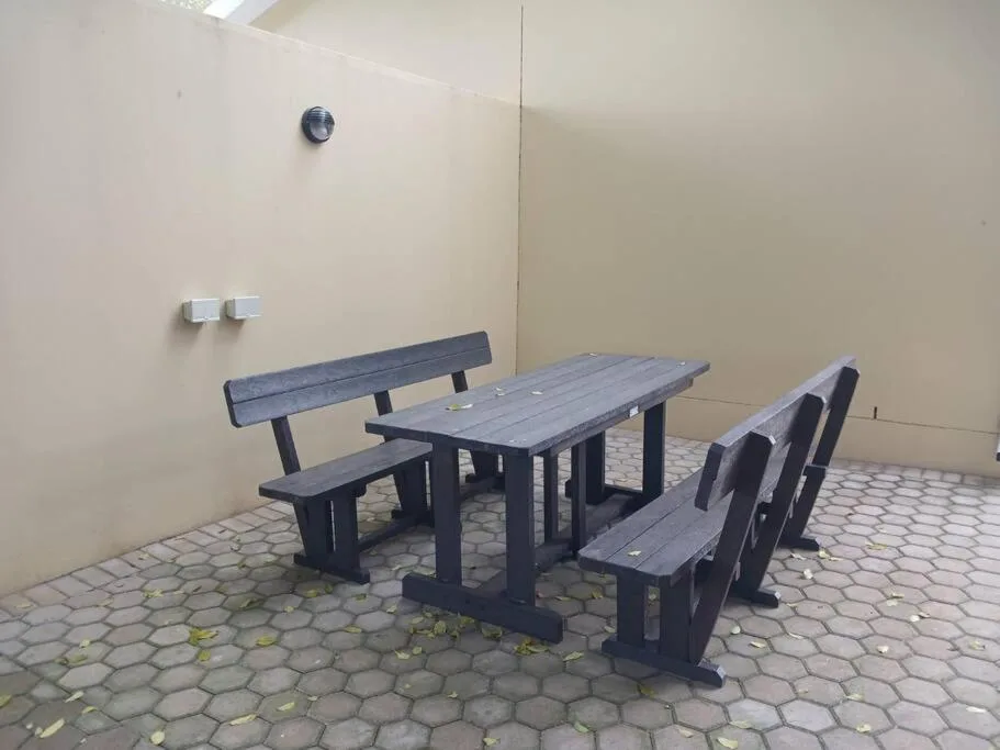Outdoor dining area with picnic table and benches on paved patio