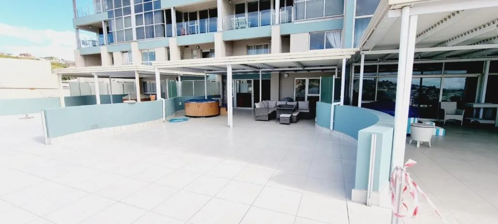 Spacious tiled patio with seating and hot tub overlooking coastal surroundings