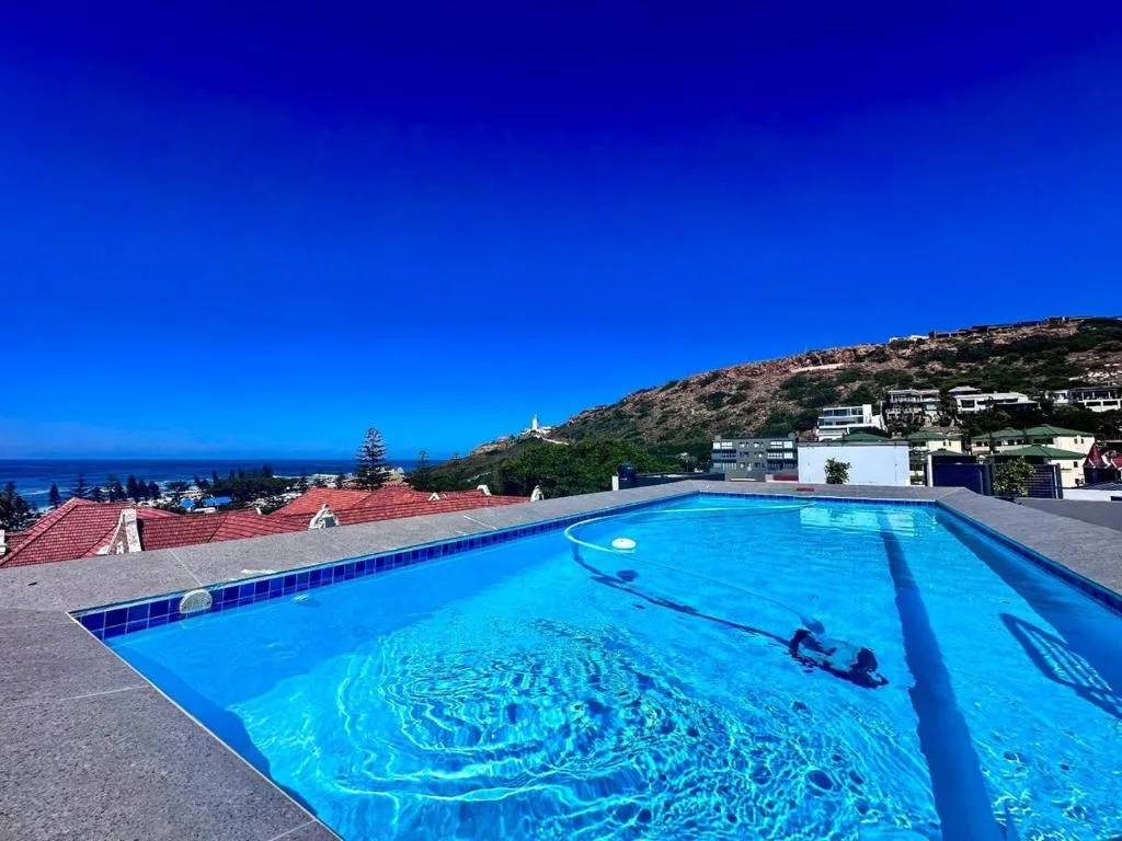 Bright blue swimming pool overlooking coastal hills and ocean vista