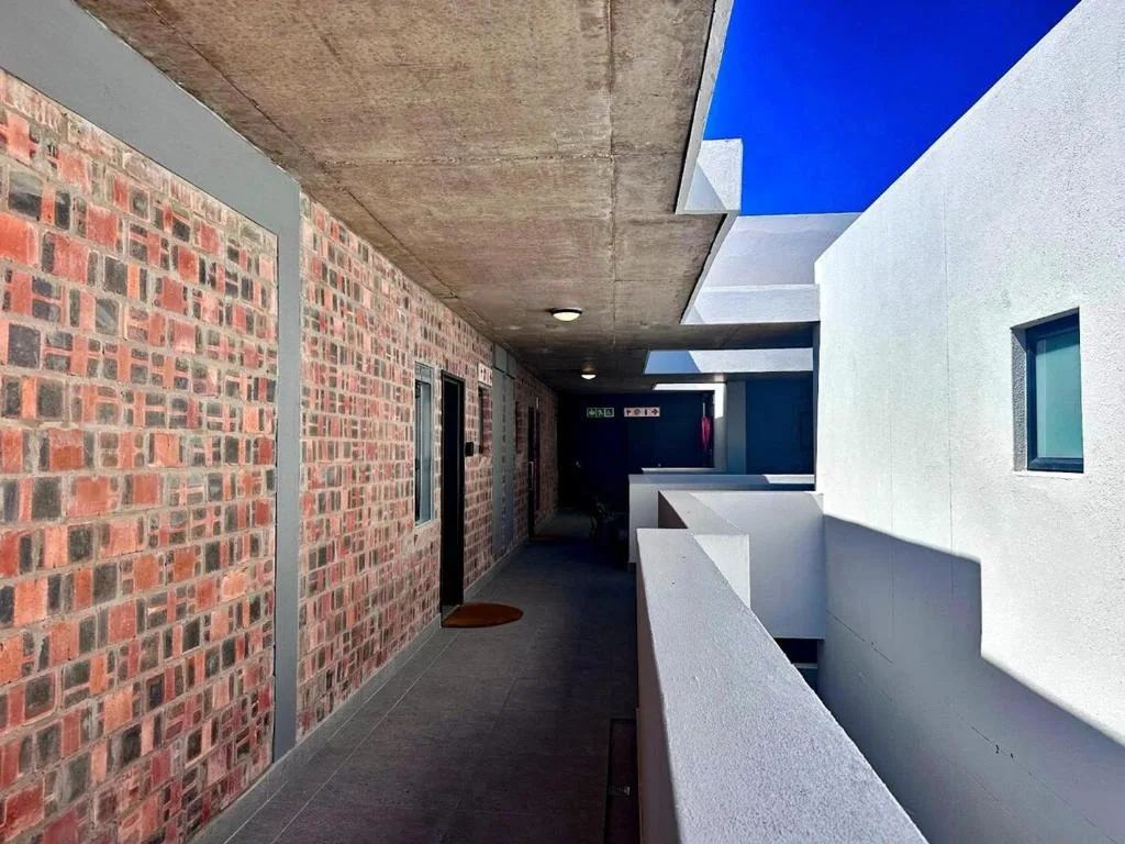 Modern covered walkway with exposed brick walls and white railings