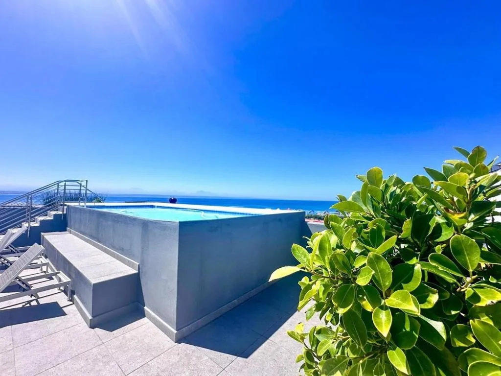 Modern infinity pool overlooking the ocean on a sunny coastal deck
