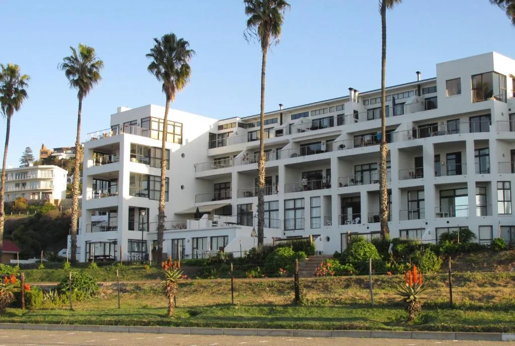 Modern white apartment building with multiple balconies and palm trees, Garden Route