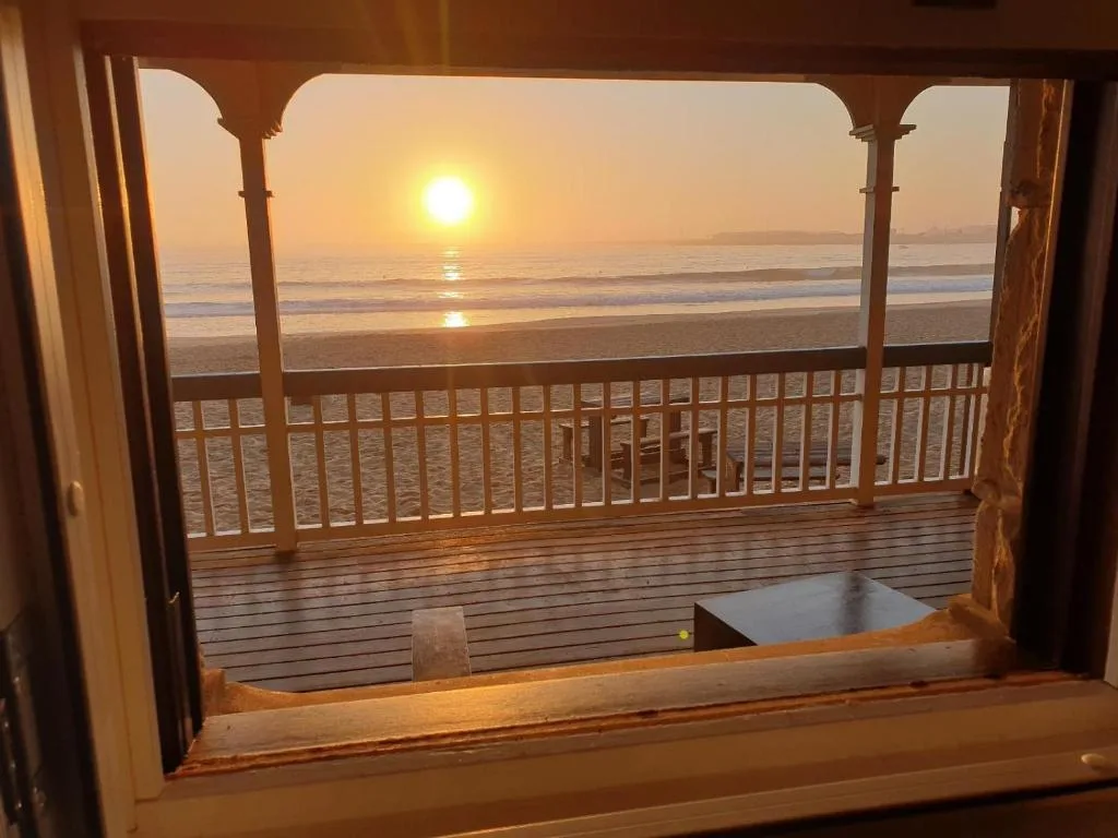 Sunset over ocean and beach viewed from wooden deck with railing