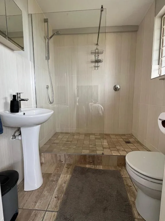 Spacious bathroom with walk-in shower, pedestal sink, and toilet