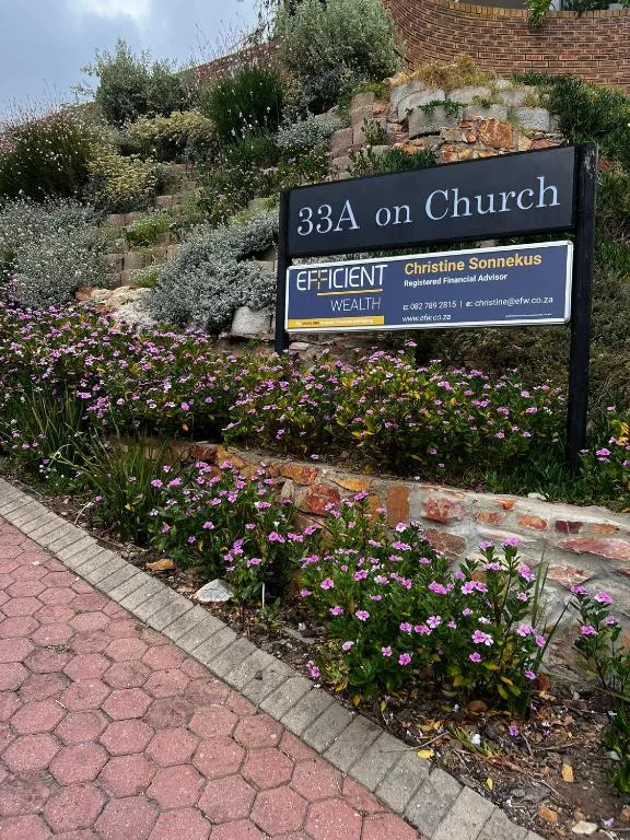 Property entrance sign with flowering garden and brick building facade