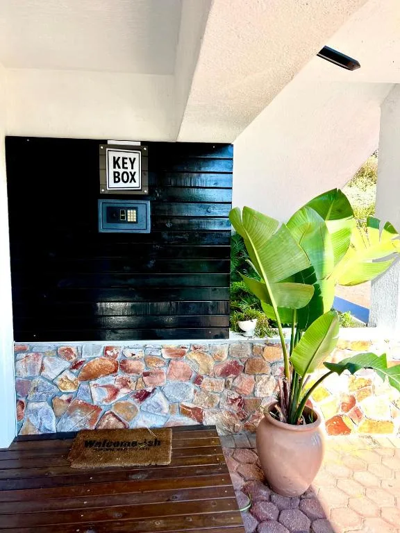 Black painted entrance door with key box, potted plant, wooden deck