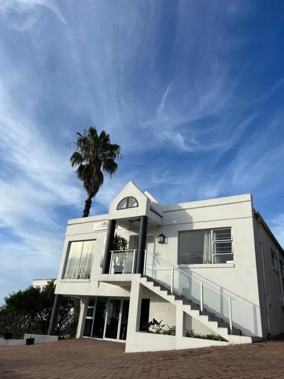 Modern white apartment building with palm tree and blue sky backdrop