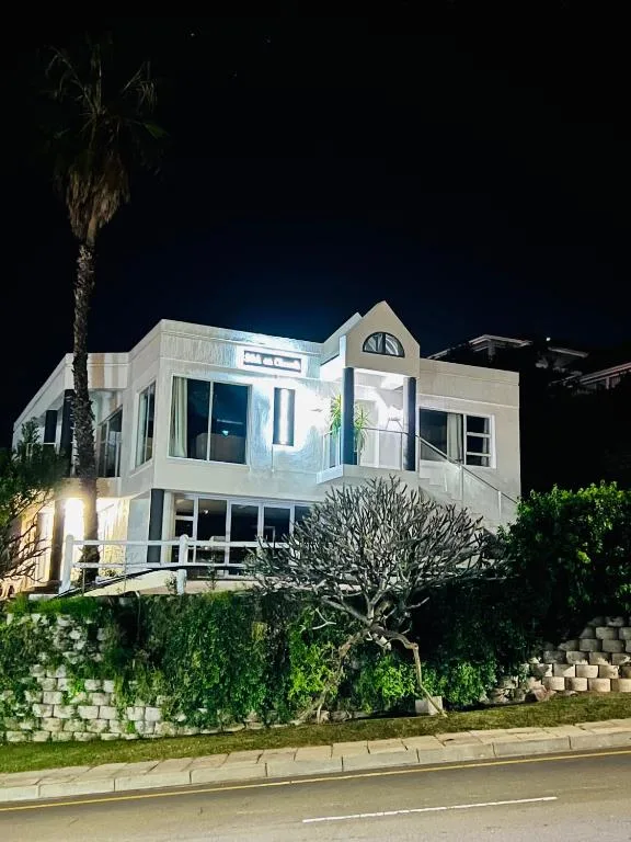 Modern white residential building photographed at night with landscaping and palm tree