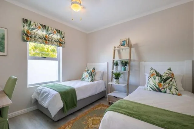 Bright twin bedroom with green accents and botanical-themed decor throughout