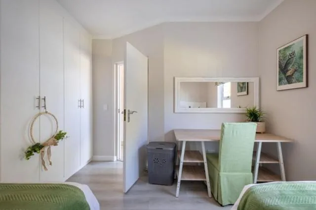 Bedroom with twin beds, vanity desk, wardrobe, and soft natural light