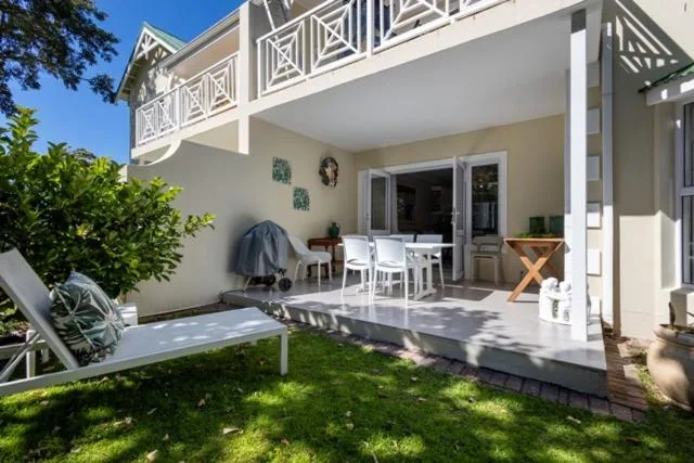 Covered patio with dining table, lounge chairs, and manicured lawn