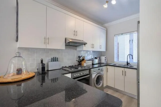 Modern kitchen with white cabinetry, dark granite counters, and stainless steel appliances