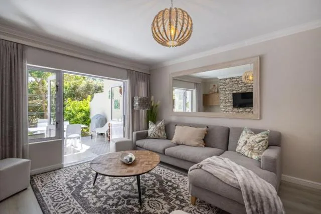 Contemporary lounge with gray sofa, wooden pendant light, and garden views