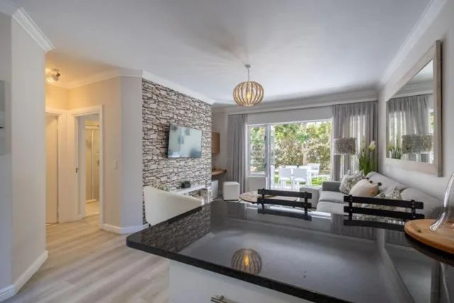 Modern lounge with brick feature wall, TV, seating, and garden views