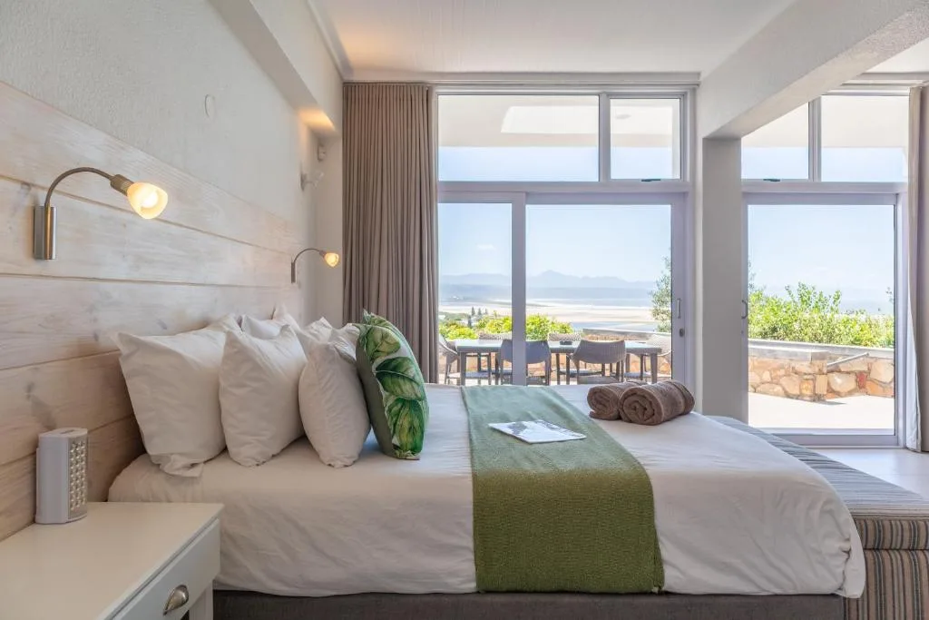 Bright bedroom with sea view through large sliding doors and coastal landscape beyond