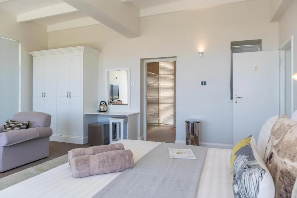 Spacious bedroom with bed, wardrobe, vanity desk, and ensuite bathroom access