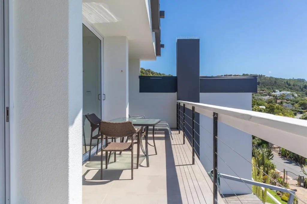 Modern deck with table, chairs, and forested hillside views beyond