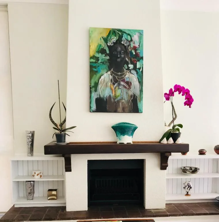 Fireplace mantel with artwork, plants, and decorative shelving display