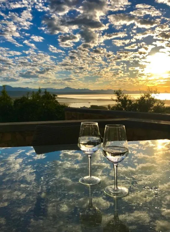 Wine glasses on deck overlooking lagoon at golden sunset hour