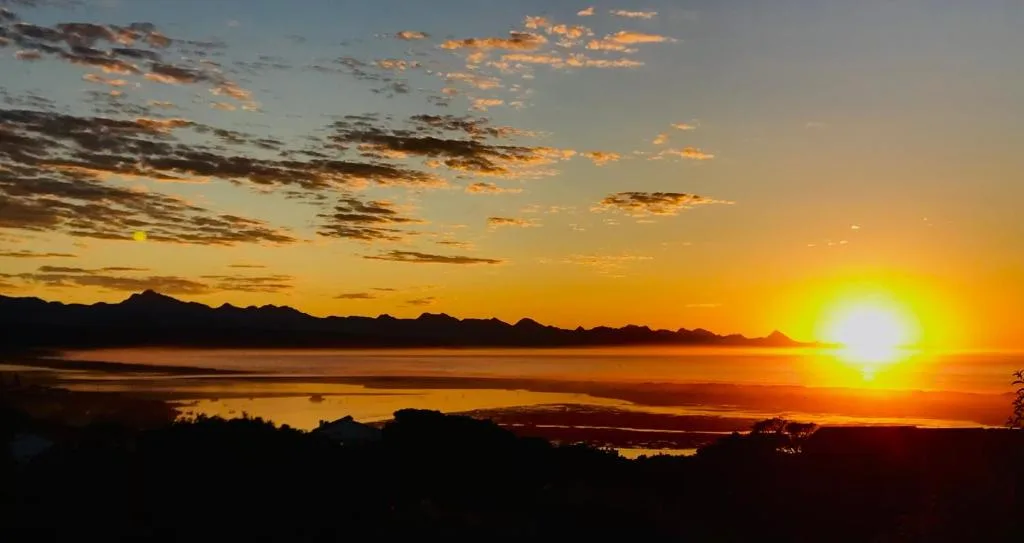 Golden sunset over Plettenberg Bay lagoon with distant mountains silhouetted