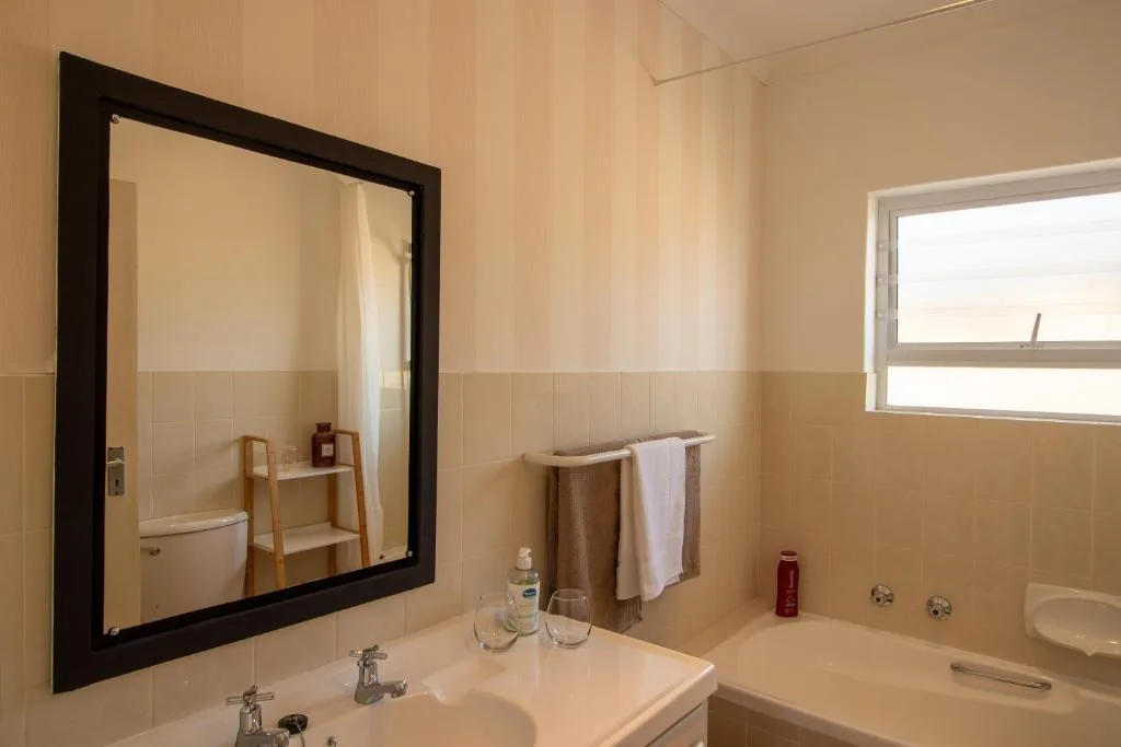 Bathroom with vanity, mirror, toilet, and bathtub with window
