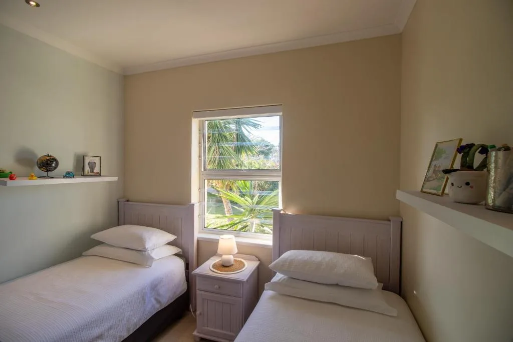 Twin bedroom with white bedding, tropical garden view through window